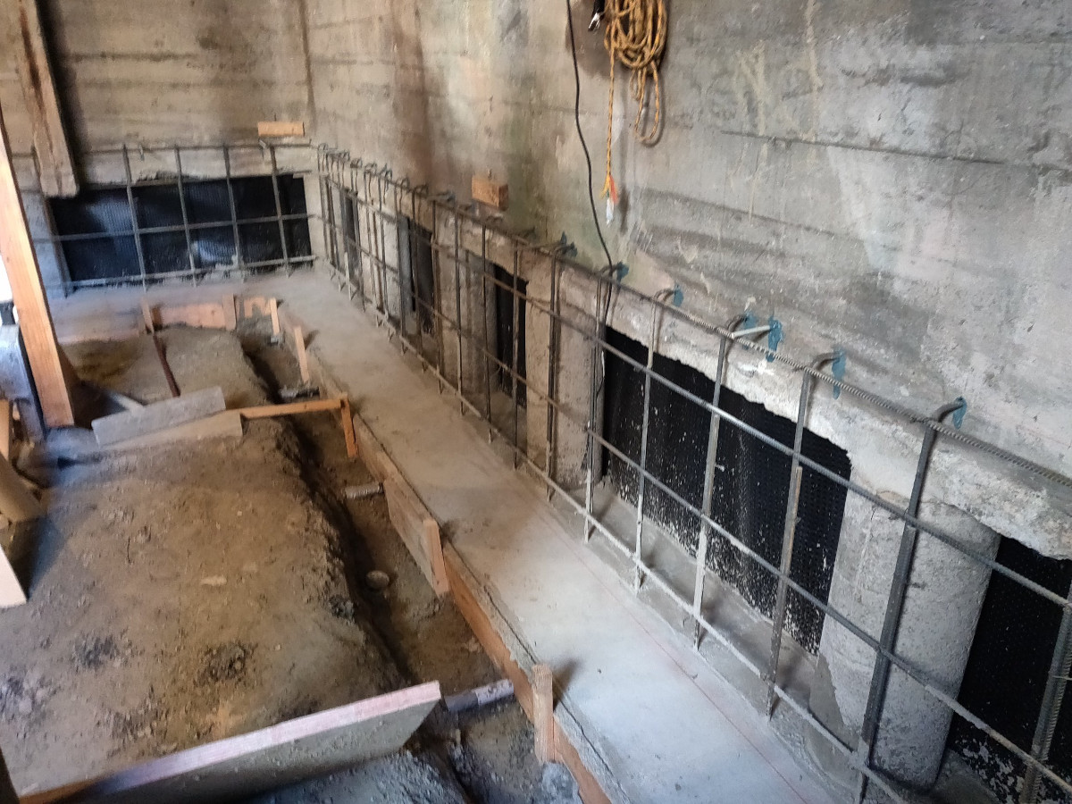 Footing trench and drainage board along a Seattle basement wall during underpinning