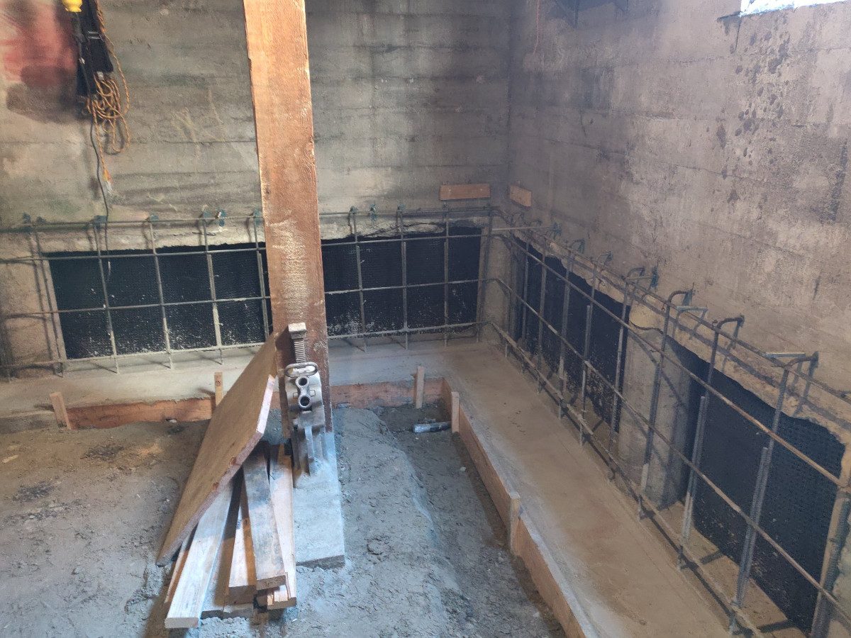 Rebar cage and formwork set against a Seattle basement wall for a replacement foundation