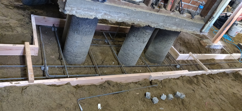 New concrete piers and reinforced footing forms poured beneath a Seattle home during foundation replacement