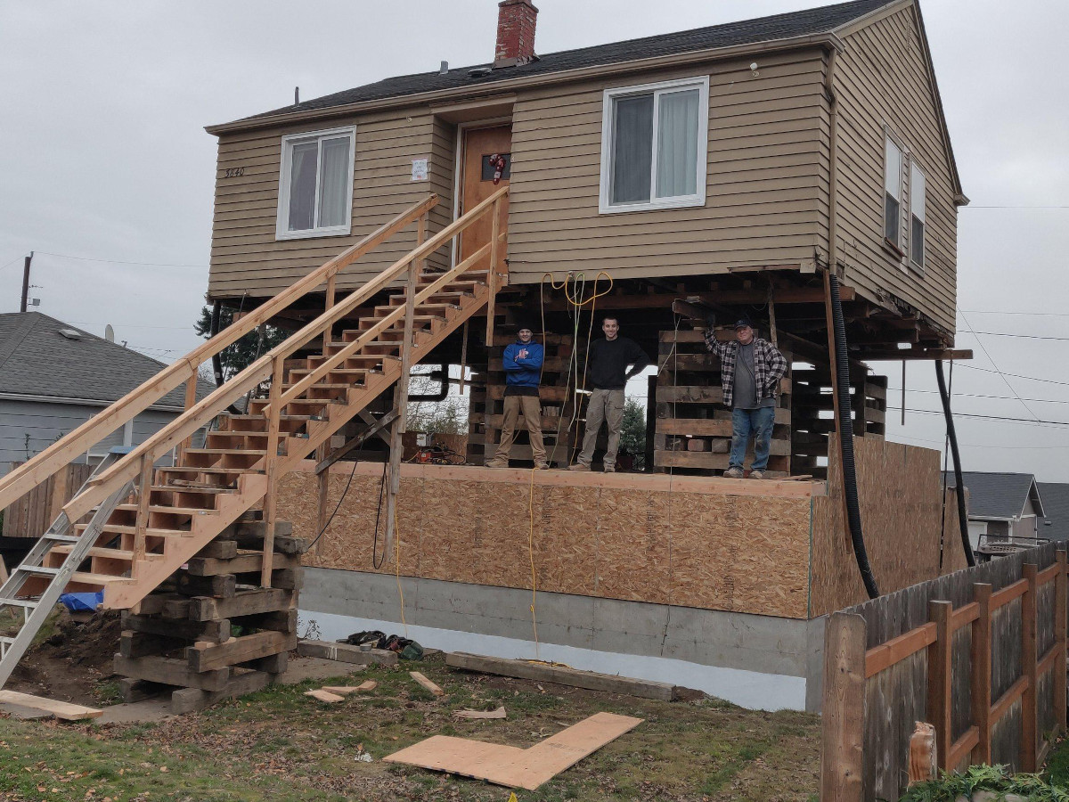 Crew standing in the new first floor framed beneath a lifted Seattle home