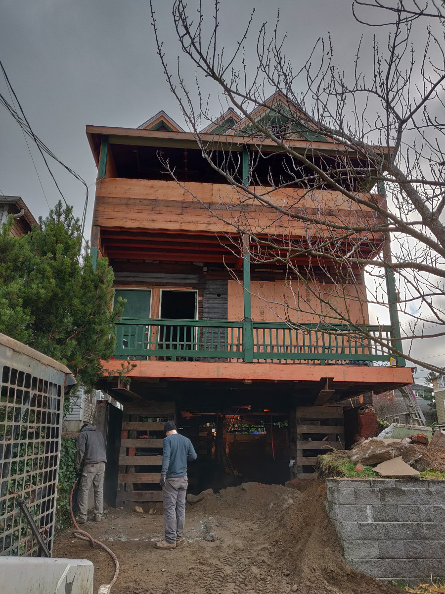 Seattle home held on cribbing while the crew excavates the ground beneath it