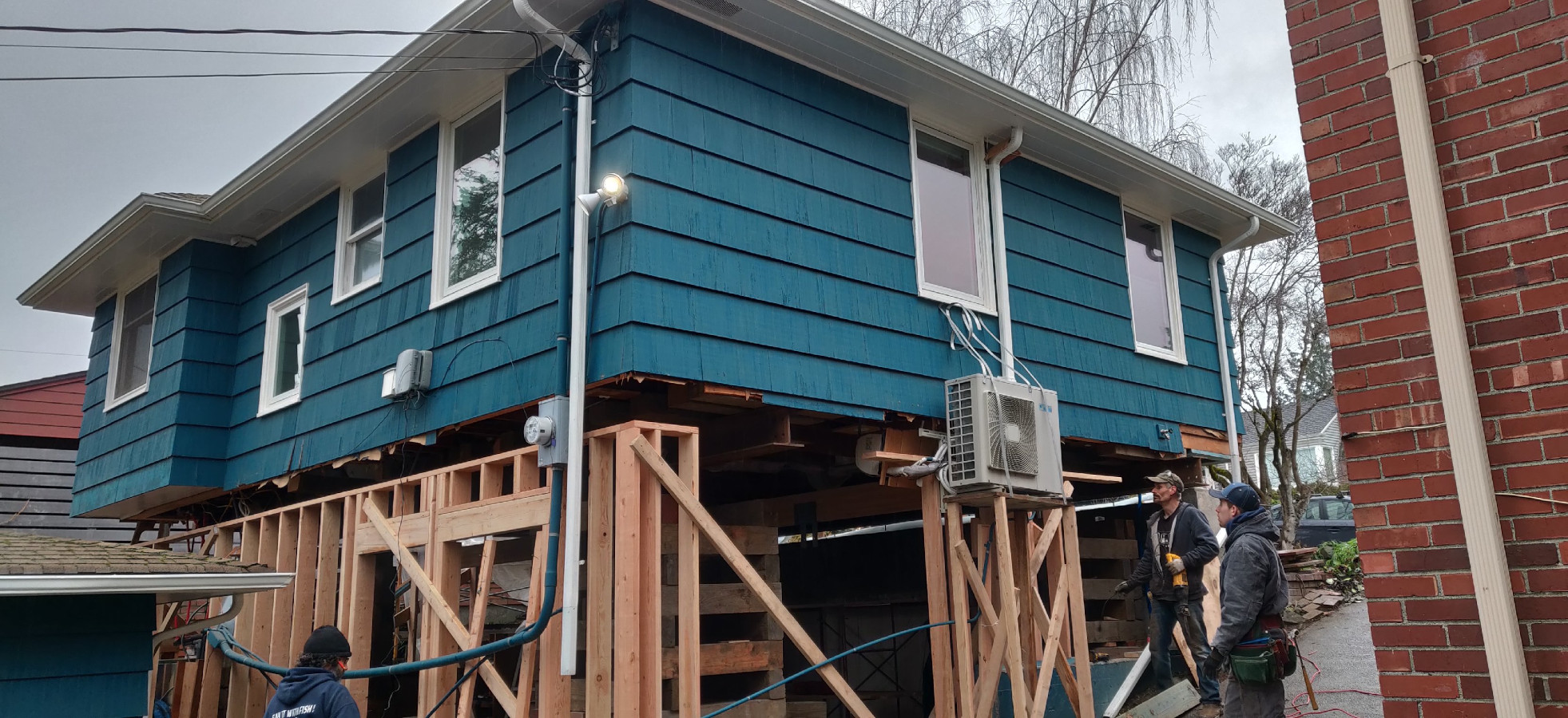 New posts and beams carrying a Seattle home while the crew frames below